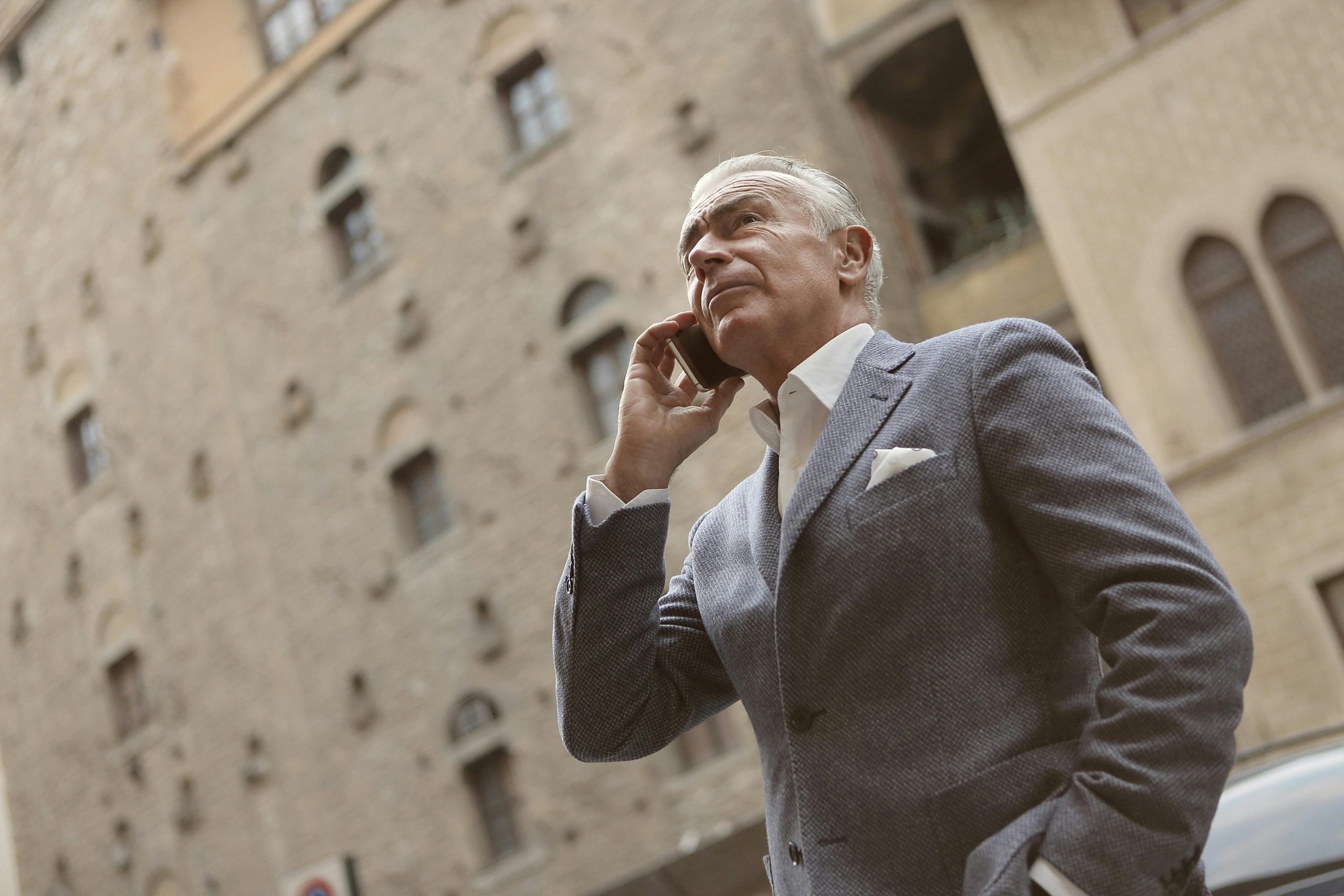 Senior businessman outdoors using smartphone for communication. Urban setting.